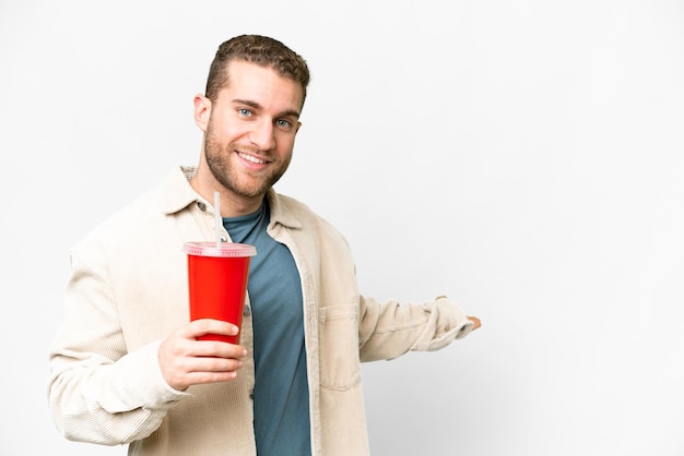 Young handsome blonde man holding soda over isolated white background extending hands to the side for inviting to come