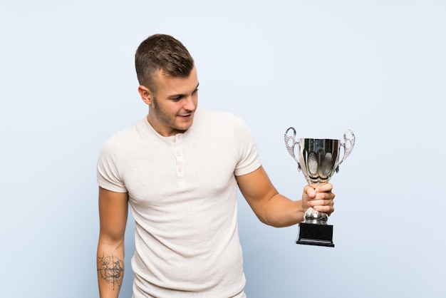Foto giovane uomo biondo bello che tiene un trofeo