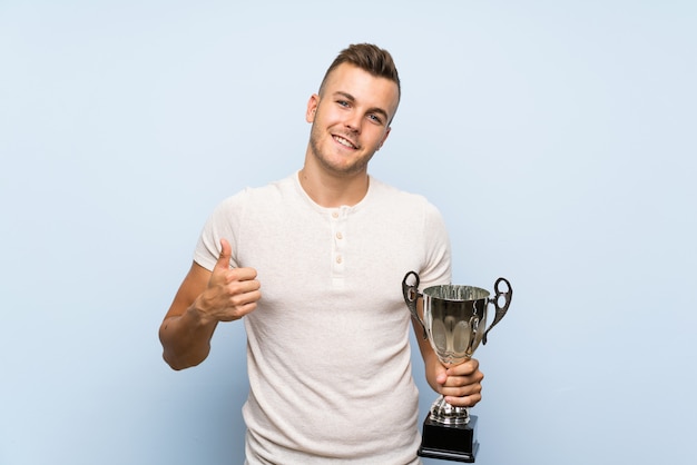 Young handsome blonde man holding a trophy