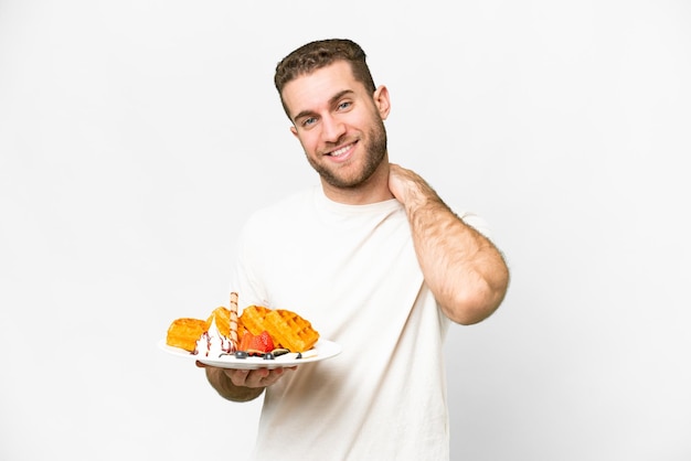 Young handsome blonde man holding waffles over isolated white background laughing