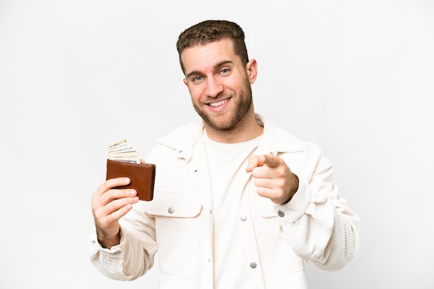 Young handsome blonde man holding a wallet over isolated white background points finger at you with a confident expression