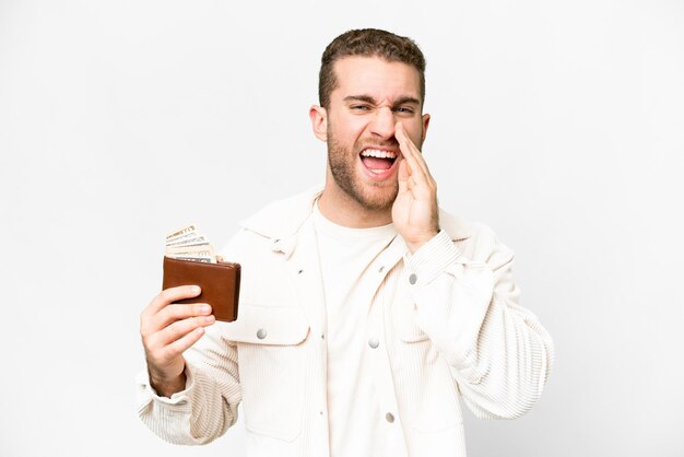 Young handsome blonde man holding a wallet over isolated white background shouting with mouth wide open