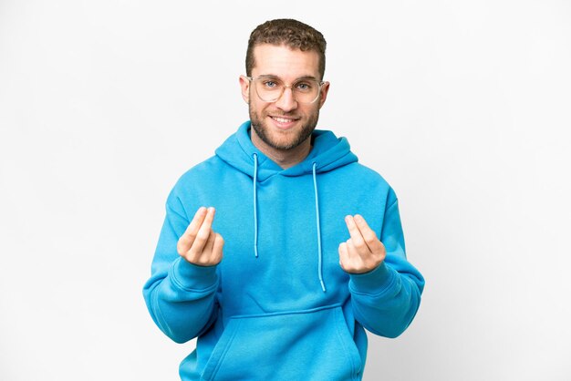 Young handsome blonde man over isolated white background making money gesture
