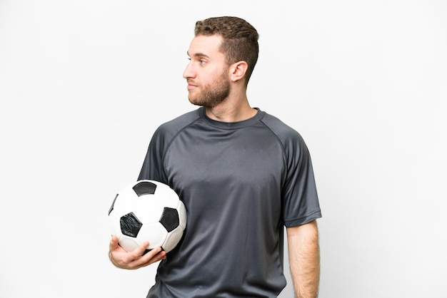 Young handsome blonde man over isolated white background with soccer ball