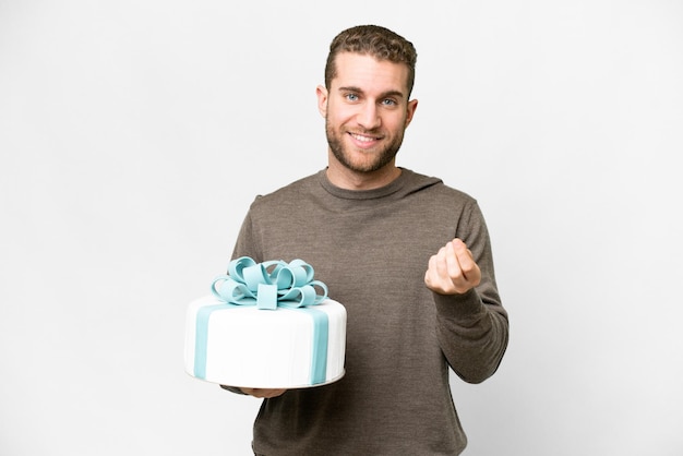 Young handsome blonde man with a big cake over isolated white background making money gesture