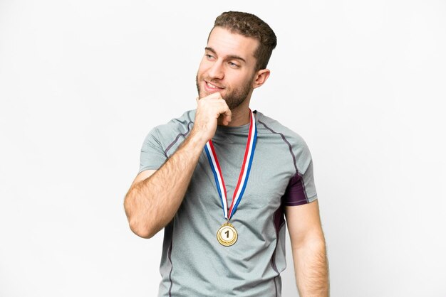 Young handsome blonde man with medals over isolated white background looking to the side