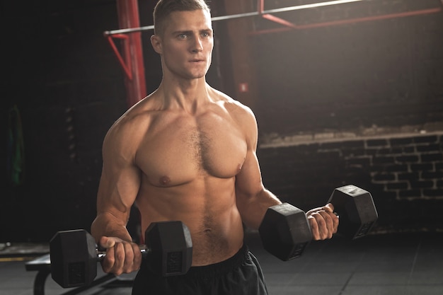 Young handsome bodybuilder during his arm workout in the gym