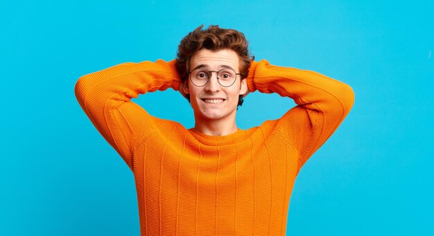 Young handsome boy feeling stressed, worried, anxious or scared, with hands on head, panicking at mistake