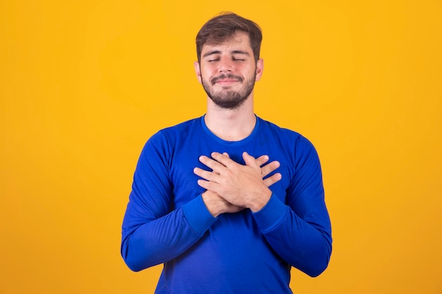 Young handsome boy has his hands on his chest near his heart human emotions real feelings and facial expression concept