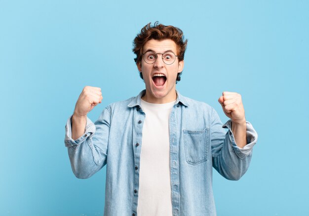 Young handsome boy shouting aggressively with an angry expression or with fists clenched celebrating success