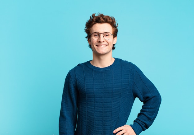 Young handsome boy smiling happily with a hand on hip and confident, positive, proud and friendly attitude