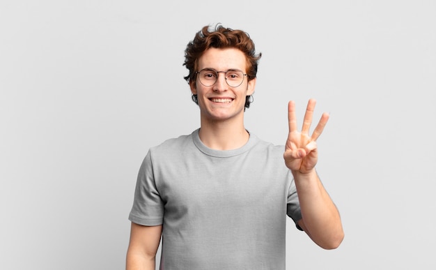 Young handsome boy smiling and looking friendly, showing number three or third with hand forward, counting down