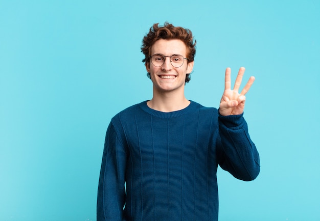 Young handsome boy smiling and looking friendly, showing number three or third with hand forward, counting down