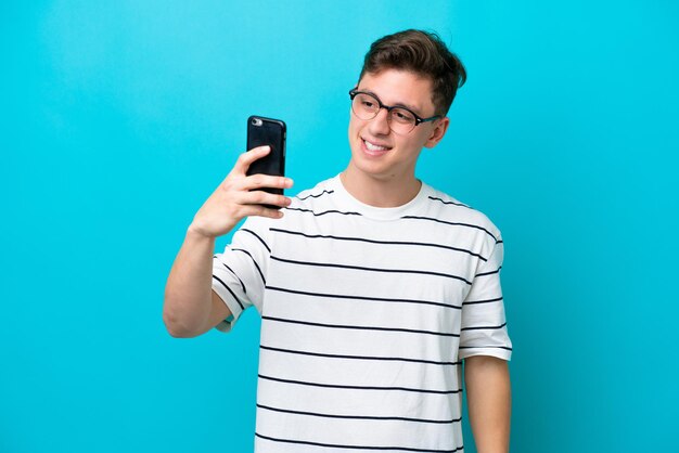 Young handsome Brazilian man isolated on blue background making a selfie