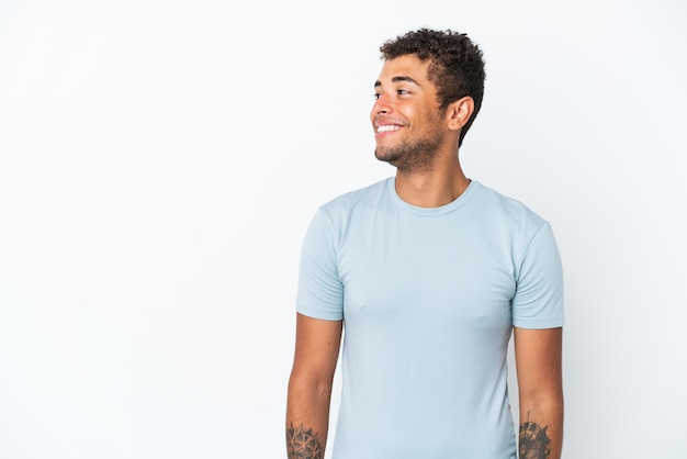 young handsome brazilian man isolated on white background looking to the side and smiling