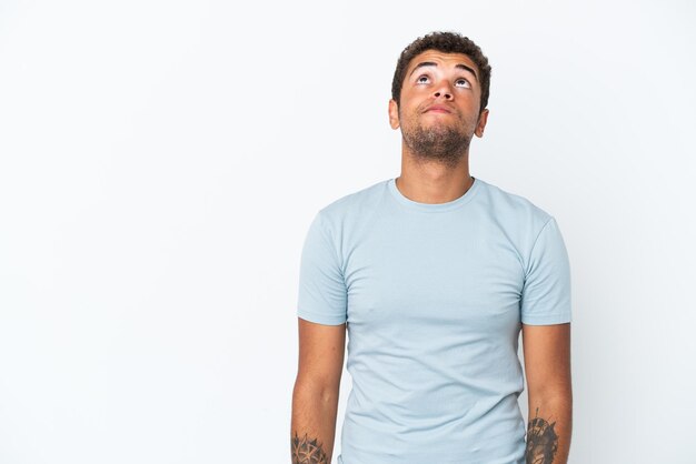 Young handsome Brazilian man isolated on white background and looking up