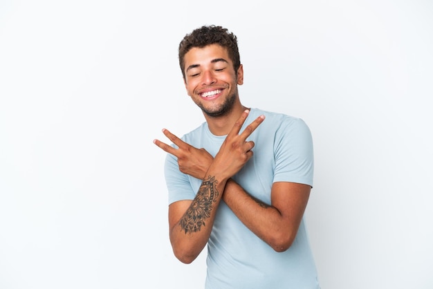 Young handsome Brazilian man isolated on white background smiling and showing victory sign
