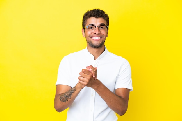 Young handsome Brazilian man isolated on yellow background laughing