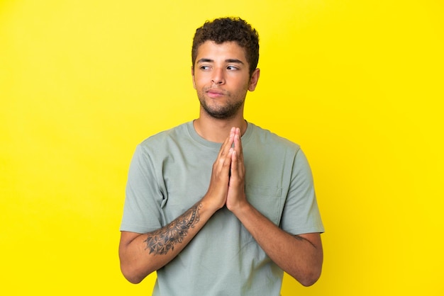 Young handsome Brazilian man isolated on yellow background scheming something