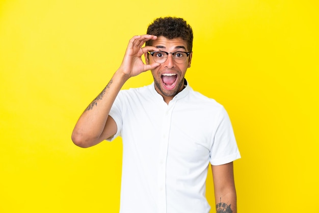 Young handsome Brazilian man isolated on yellow background showing ok sign with fingers