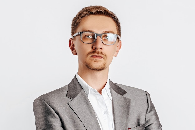 Young handsome brunet man in glasses in suit on white isolated background