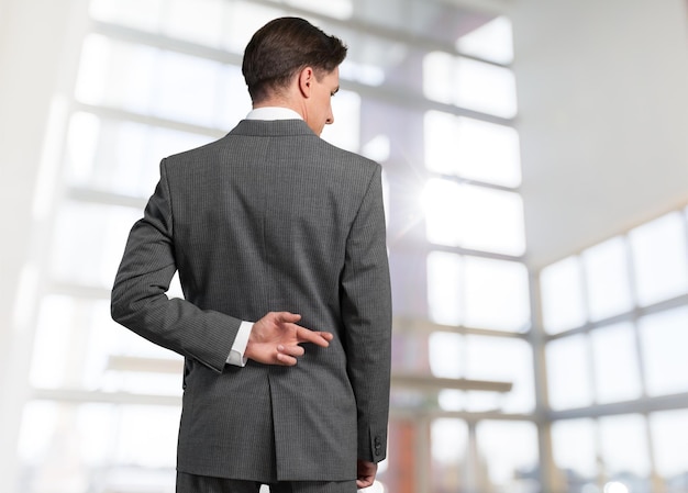 Young handsome business man in grey suit crossing fingers