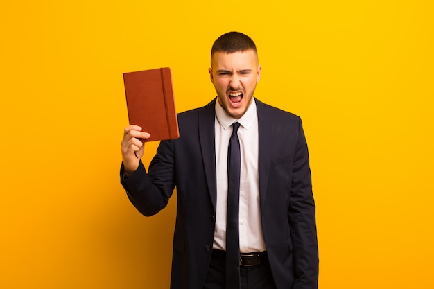 Young handsome businessman  against flat background with a diary book