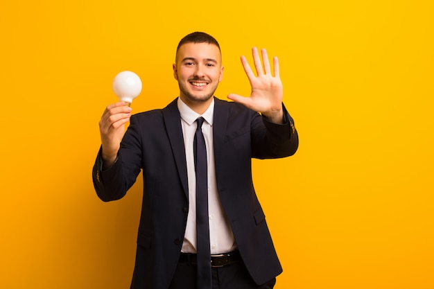 Young handsome businessman  against flat background with a light bulb