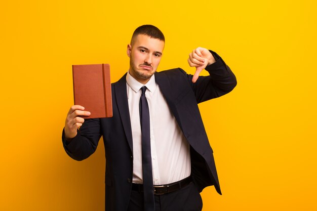 Young handsome businessman  against flat wall with a diary book