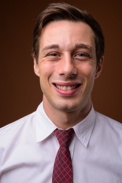 Young handsome businessman on brown wall