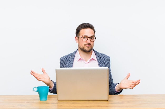 Young handsome businessman feeling puzzled and confused, unsure about the correct answer or decision, trying to make a choice