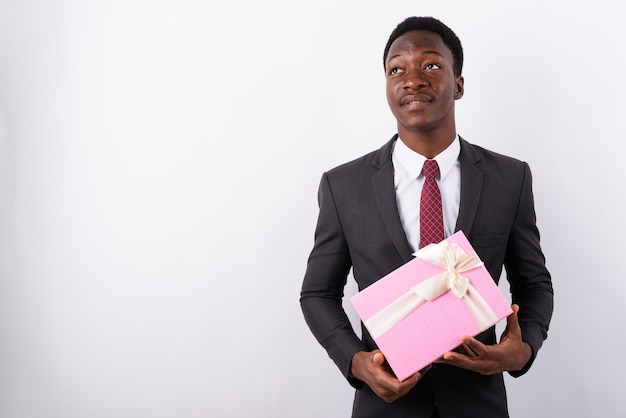 Young handsome businessman holding gift box against white