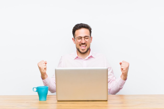 Young handsome businessman looking extremely happy and surprised