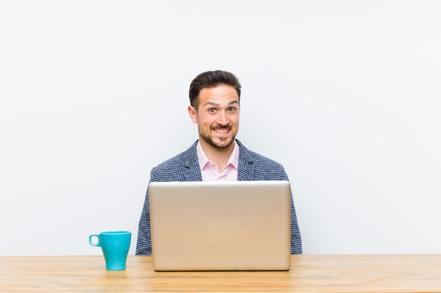 Young handsome businessman looking happy and pleasantly surprised excited with a fascinated and shocked expression