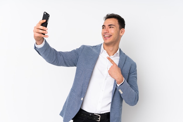Молодой красивый бизнесмен на стене делая selfie