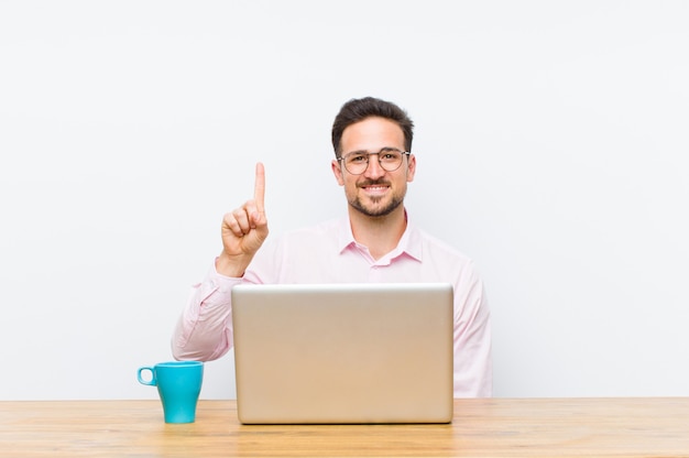 Young handsome businessman smiling and looking friendly, showing number one or first with hand forward, counting down