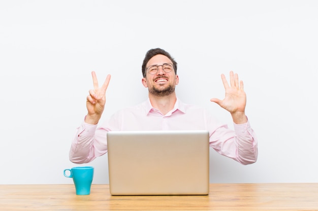 Young handsome businessman smiling and looking friendly, showing number seven or seventh with hand forward, counting down