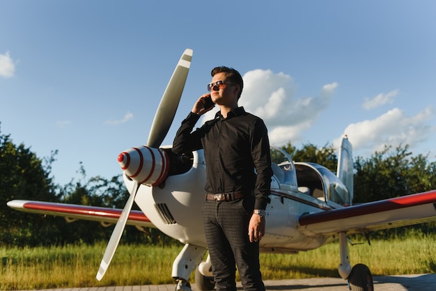 Young handsome businessman standing near private plane