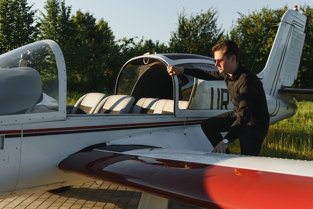 Foto giovane uomo d'affari bello che sta vicino all'aereo privato