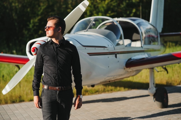 Young handsome businessman standing near private plane