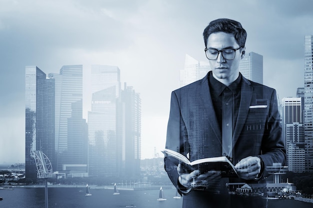 Young handsome businessman in suit and glasses thinking how to tackle the problem new career opportunities MBA assignment Singapore on background Double exposure