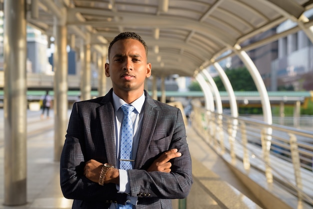 Young handsome businessman in suit with arms crossed in the city