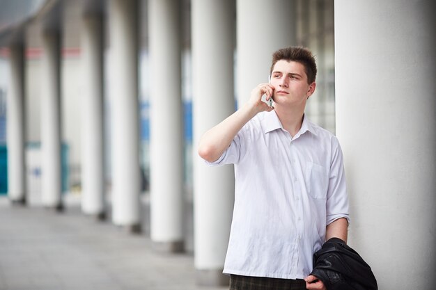 Young handsome businessman talking on the phone in the street 