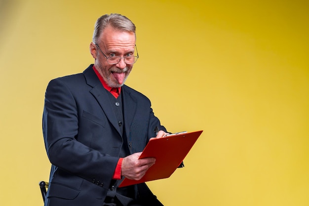 Young handsome businessman wearing elegant shirt over isolated yellow background sticking tongue out happy with funny expression Emotion concept