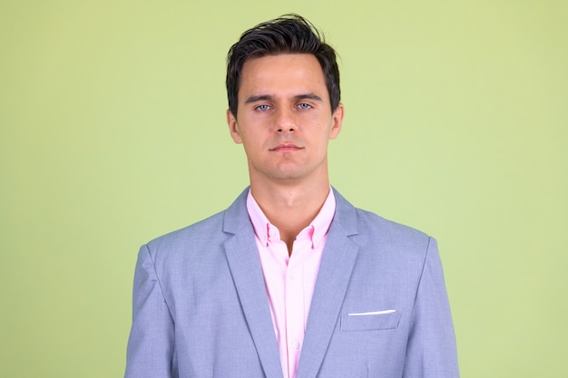  young handsome businessman wearing suit against colored wall