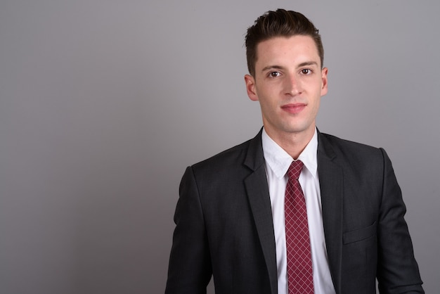 young handsome businessman wearing suit on gray