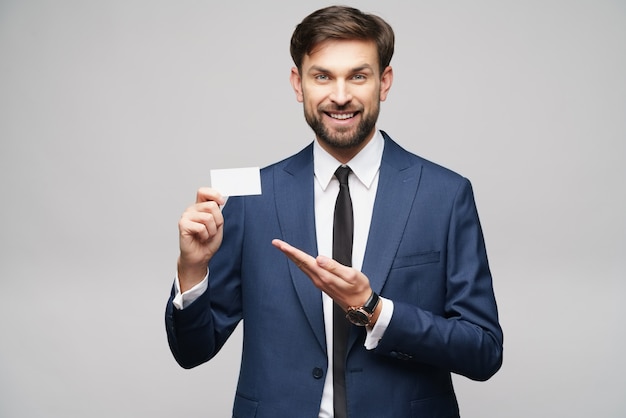 young handsome businessman wearing suit holding business card