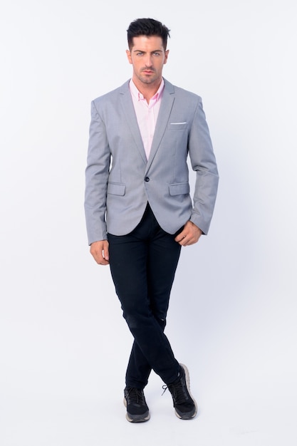 young handsome businessman wearing suit isolated against white wall