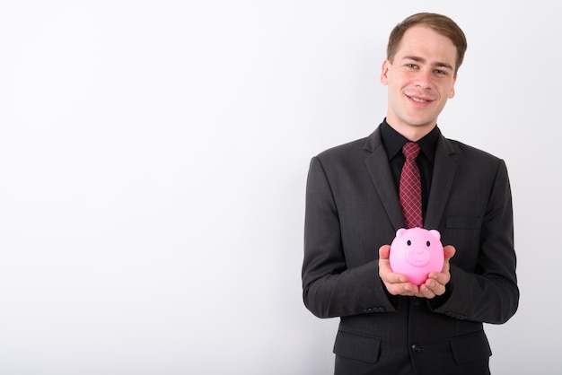 Young handsome businessman wearing suit on white wall