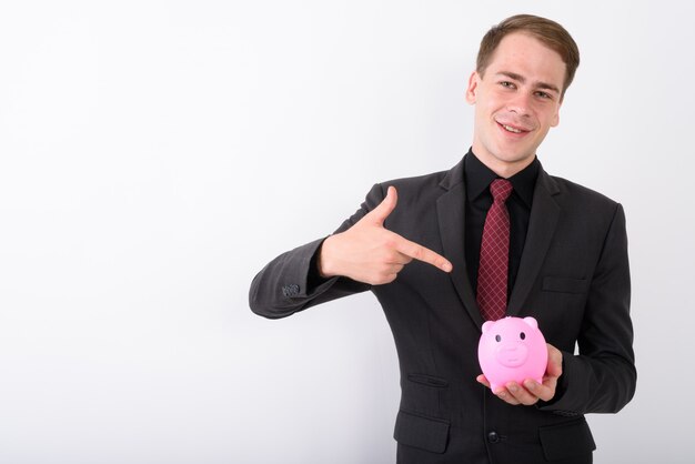 Young handsome businessman wearing suit on white wall